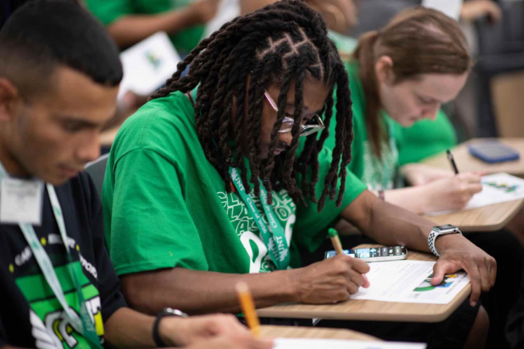 A student in a green shirt writes 