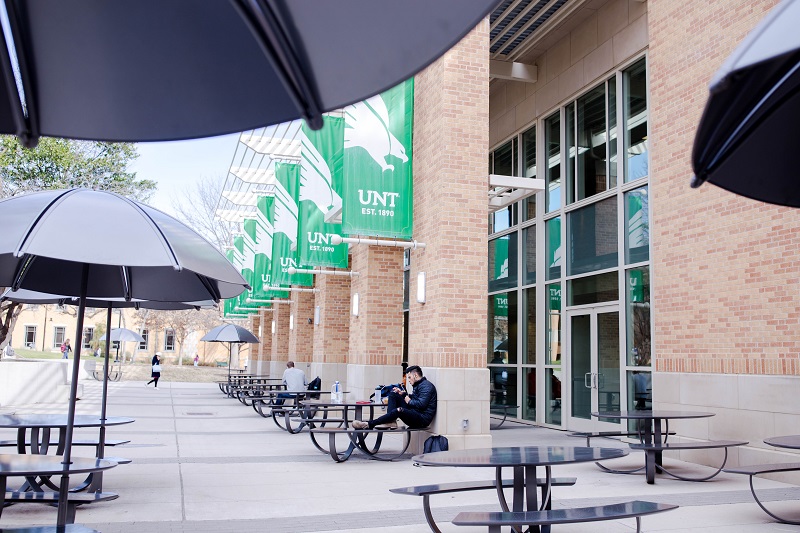 A student sitting outside the UNT building